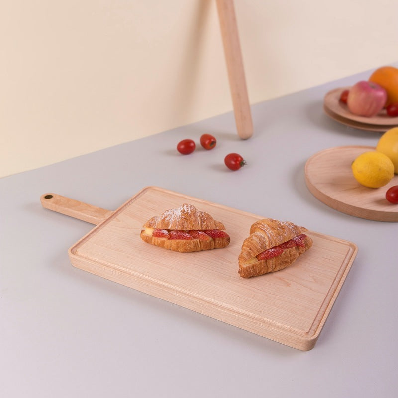 The Maple Wooden Cutting Board with croissant pastries on it.