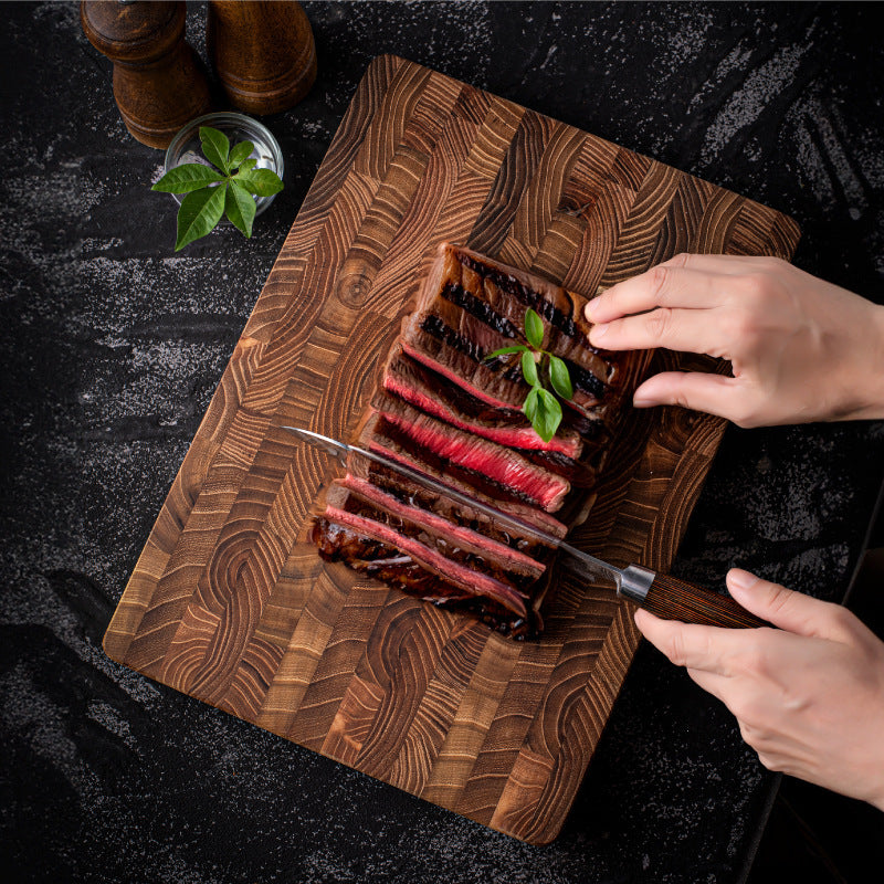 The Walnut Wood Chopping Board with a rare steak that is cut up on it. It shows the amazing wood grain and rich wood color.