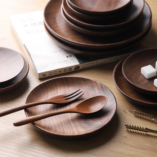Black Walnut Plates stacked on top of each other with wooded utensils on them