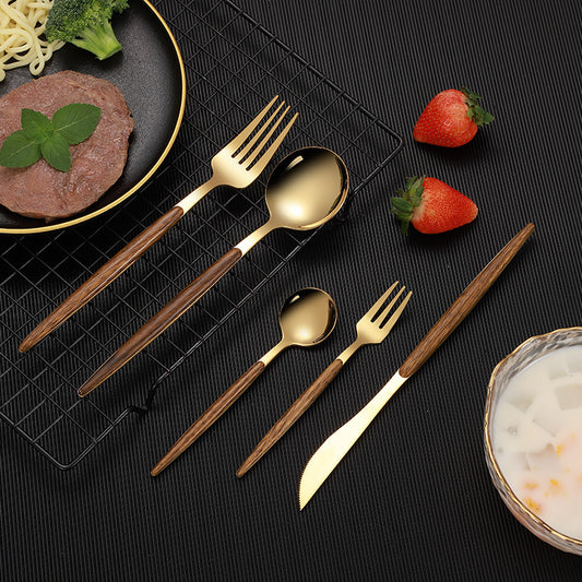 The gold 5-Piece Cutlery Set With Wood Handle stacked next to a table set.