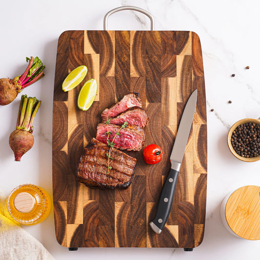 The Acacia End-Grain Wood Cutting Board with steak being cut on it.