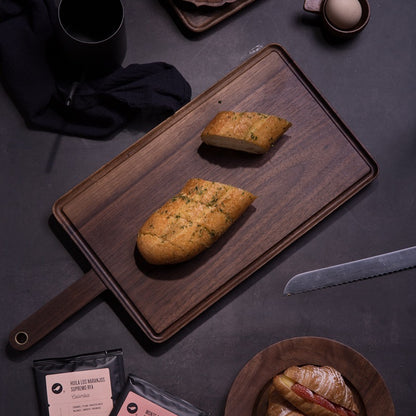 The Product image of the Black Walnut Wooden Cutting Board with garlic bread on it.