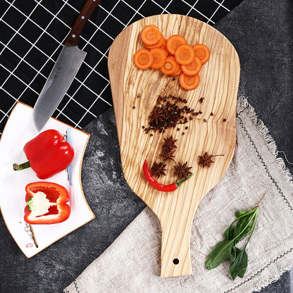 The Olive Wood Irregular Cutting Board with cut carrots and peppers on it.