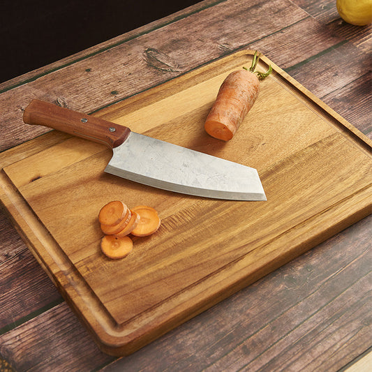 The Solid Acacia Wooden Cutting Board with a carrot being cut. You can see the wood grain and deep wood color.