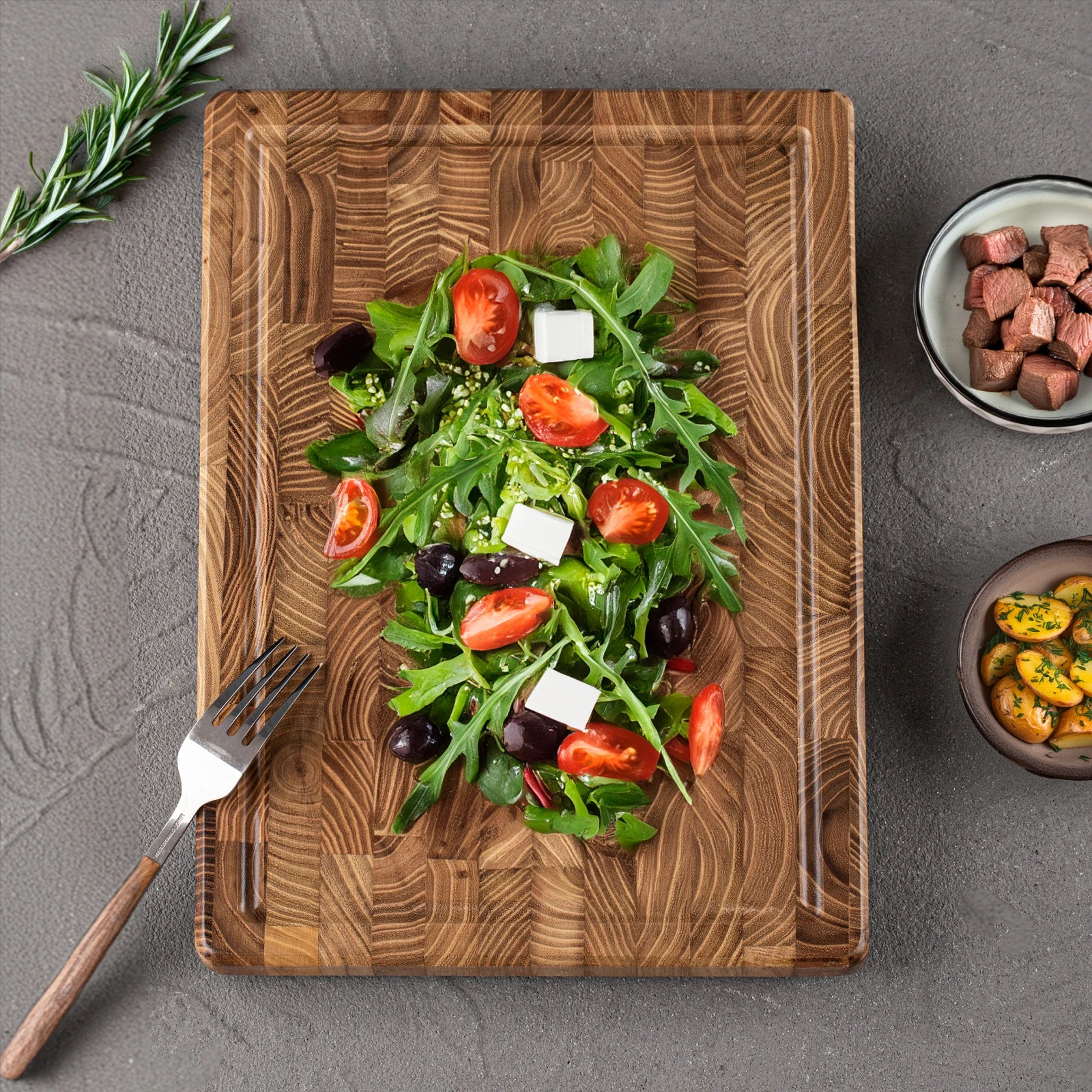 The Teak Wood End-Grain Cutting Board with salad, and tomatoes on it.