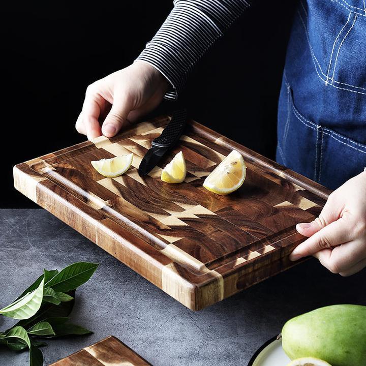The Parquet Acacia Wood Cutting Board with a half a lemon cut on it. Showing the beautiful wood grain and dark rich wood color.