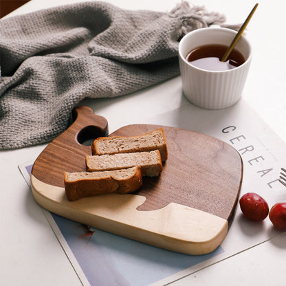 The small Black Walnut and Maple Whale Cutting Board with bread on it. Showing the beautiful wood grain and dark coloring.