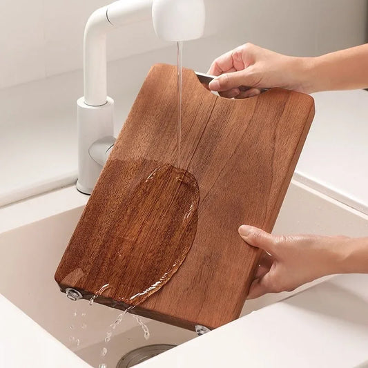 The small Ebony One-Piece Wood Cutting Board being washed under water.