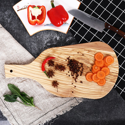The Olive Wood Irregular Cutting Board with carrots and spices on it.