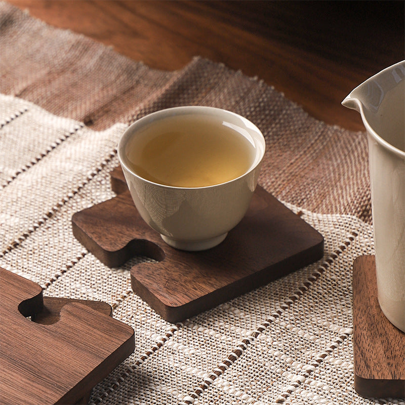 White tea cup on the Black Walnut Puzzle Wood Coaster, showing the wood color and grain.